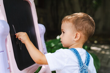 A little boy writing on a blackboard. The Curious Little Scholar Unleashing His Creativity on the...