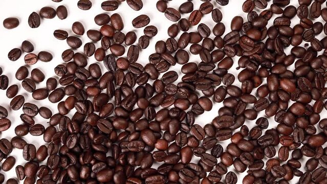 Video footage of coffee beans hitting each other in the center of an image on a white background.