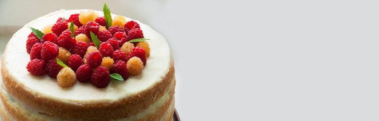 sponge cream cake with ripe red and yellow raspberries. fresh, colorful and delicious dessert with juicy raspberries and sweet whipped cream. The concept of home baking fruit