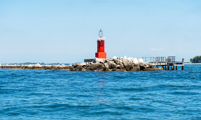Red lighthouse in the sea, sunny day. Ligniano, St.Andrea island, Friuli, Italy