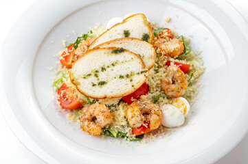 caesar salad with shrimp in a plate on a white background