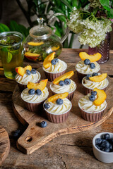 Peach mint tea and blueberry and peach cupcakes. Side view, wooden background.