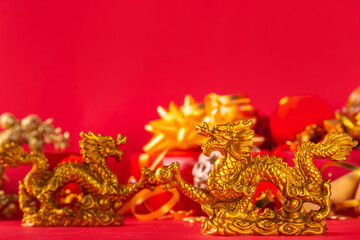Chinese New Year 2024 greeting card. Bright red asian year of the dragon background with golden dragon figurine, Chinese lanterns, traditional jewelry, gifts, coins, cookies with wishes, copy space
