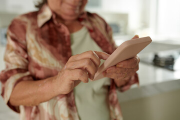 Obraz na płótnie Canvas Closeup image of senior woman checking notifications on smartphone