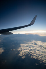 Obraz premium View of the wing of an airplane in mid-flight with clouds in the background