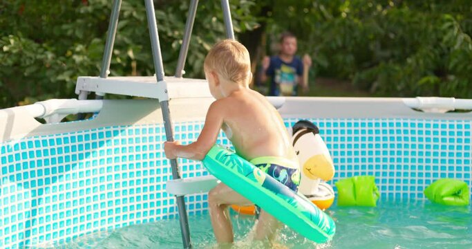 Joyful boy jumping into the pool in the backyard enjoying his summer vacation