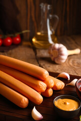Board of tasty sausages and mustard on wooden background