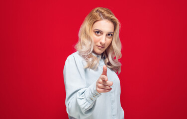 Close-up woman doing gun gesture getting ready to shoot you, girl showing gun gesture, isolated on white background