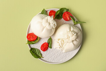 Plate with tasty Burrata cheese on green background