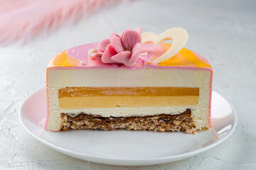 Sliced pink mousse cake with vanilla cream and mango jelly decorated with flowers and chocolate...