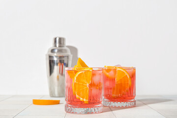 Glasses of cold Negroni cocktail on light tile table