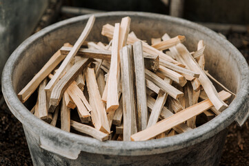 A large pile of firewood, chopped planks of wood lie in a bowl outdoors in the forest. Close-up nature photography.