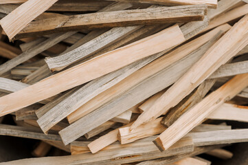 Background, background of a large pile of firewood, chopped thin planks of wood outdoors in the forest. Close-up nature photography, top view.
