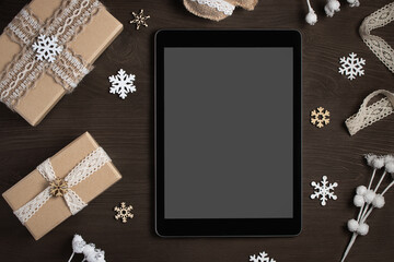 Tablet with a blank screen surrounded by Christmas decorations and gifts, mocap for advertising