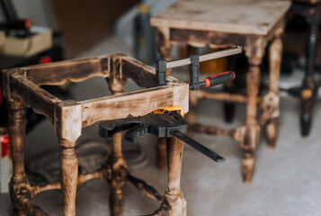 Clamp, a special tool for gluing and fixing a wooden chair in the workshop. Photography, furniture concept, craft.