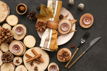 Autumn table setting with different spices, cones and burning candles on black background