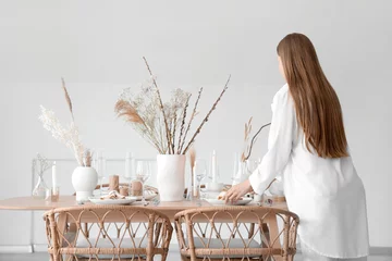 Foto op Canvas Beautiful woman setting table with dried flowers in dining room © Pixel-Shot