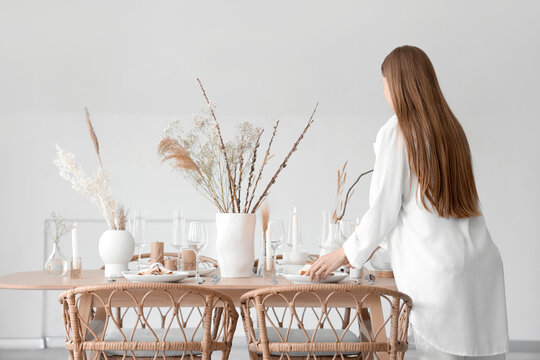 Beautiful Woman Setting Table With Dried Flowers In Dining Room