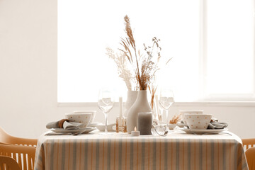 Elegant table setting with pampas grass, dried flowers and crockery in dining room