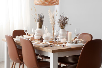 Elegant table setting with dried flowers, burning candles and pine cones