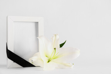 White lily and photo frame with black ribbon on white background