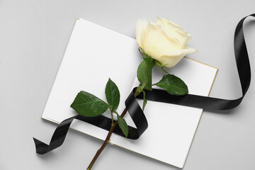 Rose with black ribbon and blank open notebook on white background
