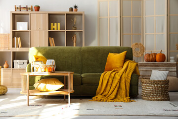 Interior of living room with green sofa and pumpkins
