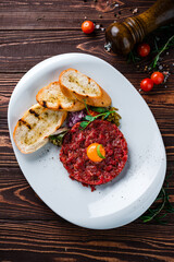Snack beef tartare with raw egg, cherry tomatoes, pickles and fried toast.