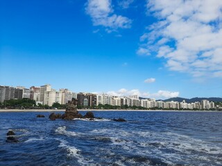 View of Icaraí Beach in Niterói, Rio de Janeiro, Brazil, with the Itapuca Rock highlighted, tall buildings and blue sky with clouds on a spring afternoon