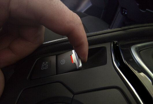 Driver pulling the electric parking brake of his car