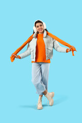 Young woman in winter clothes on blue background