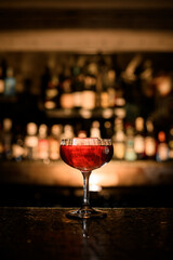 Transparent glass on a stem filled with a cocktail stands on the bar counter isolated