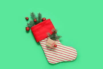 Christmas sock with fir branches, balls and gift box on green background