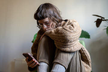 Unhappy reserved teenager holding smartphone, reading news in internet, scrolling social networks,...