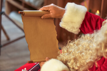 Santa Claus reading letter at home on Christmas eve, closeup