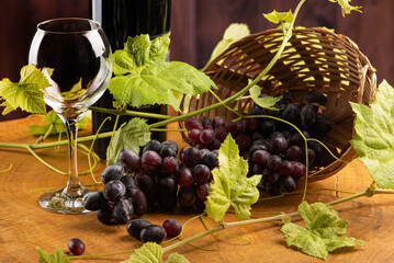 Grapes and wine, basket with beautiful grapes and bottle of red wine, on rustic wood, selective...