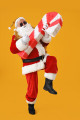Fototapeta na wymiar Cool Santa Claus with candy cane pinata on yellow background