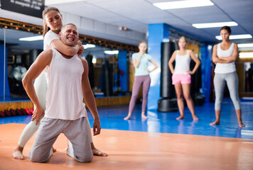 Focused young hispanic woman learning effective self defence techniques in sparring with man in...