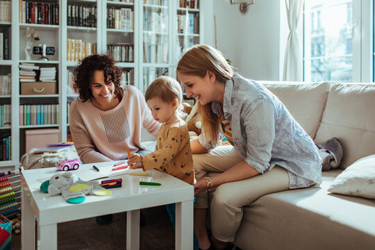 Couple of gay woman drawing with their child at home