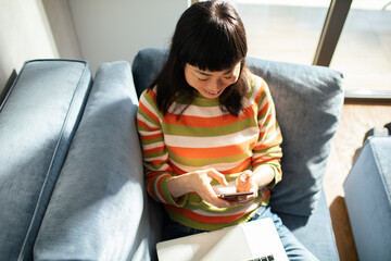 Asian woman using smartphone on couch