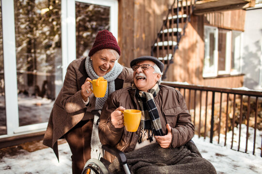 Elderly couple sharing warm moments over hot drinks in a snowy backyard
