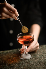 Female hands add a green leaf to the cocktail
