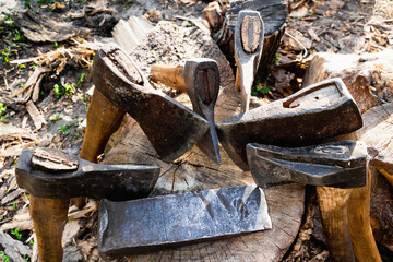 Axes with handles are placed on a wooden log. The hatchets. Harvesting firewood in the village. Craft at the countryside. Healing and longevity. Meditation of nature. Timber pantry. High resolution.
