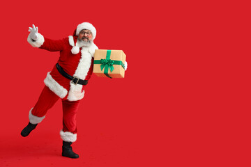 Dancing Santa Claus with gift box on red background
