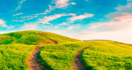 Path with hills with grass and clouds