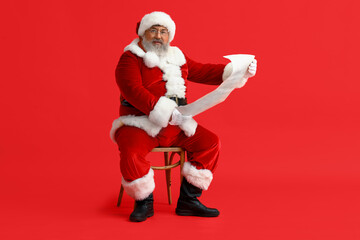 Santa Claus reading letter on red background