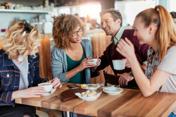 Group of happy friends having coffee in cafe