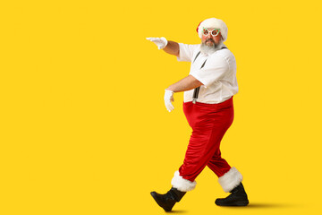 Funny Santa Claus dancing on yellow background