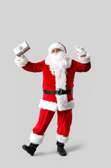 Dancing Santa Claus with gift box on grey background