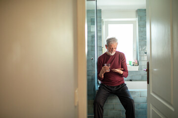Senior Man Taking Medication in Bathroom at Home